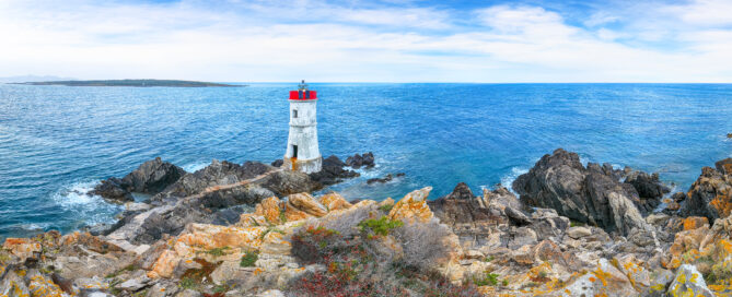 Faro bianco di Capo Ferro con scogliera e mare limpido